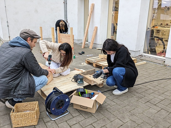 Lehrer mit Schülerinnen baut mobile Hochbeete.